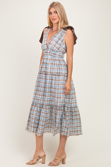 woman wearing a blue and brown checkered midi dress with ruffled sleeves and a tiered skirt