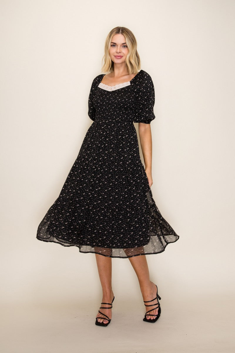 woman wearing a black floral midi dress with puff sleeves and a square neckline
