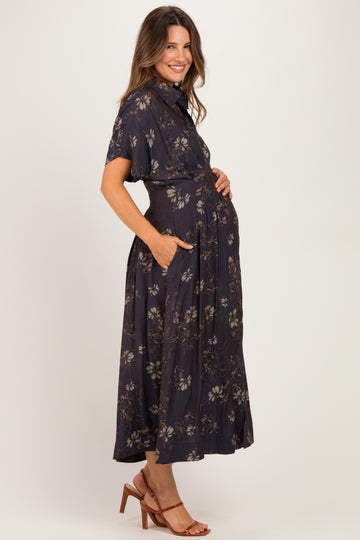 woman wearing a dark floral print maternity dress with short sleeves and pockets, showing her baby bump