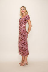 woman wearing a pink floral midi dress with puff sleeves and a ruched design
