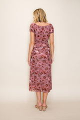 woman wearing a back view of a pink floral midi dress with short puff sleeves and a fitted silhouette