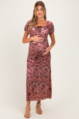 woman wearing a floral print maternity dress with short puff sleeves and a fitted bodice, cradling her baby bump