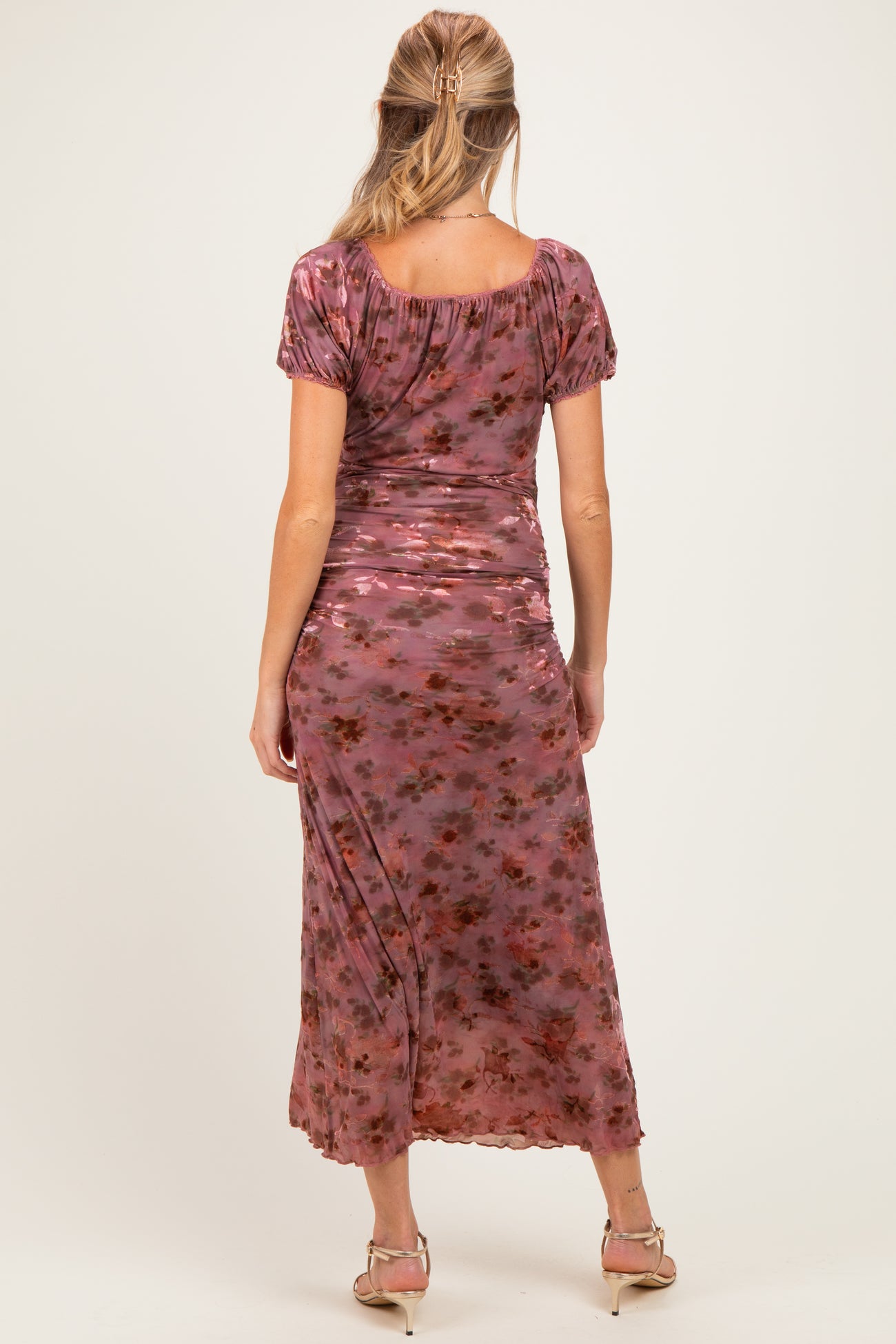 woman wearing a floral-print maternity maxi dress with short sleeves and a fitted design, showing her baby bump from the back
