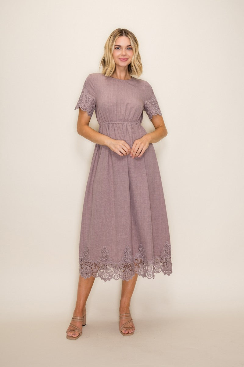 woman wearing a lavender mid-length dress with lace trim at the hem and short sleeves