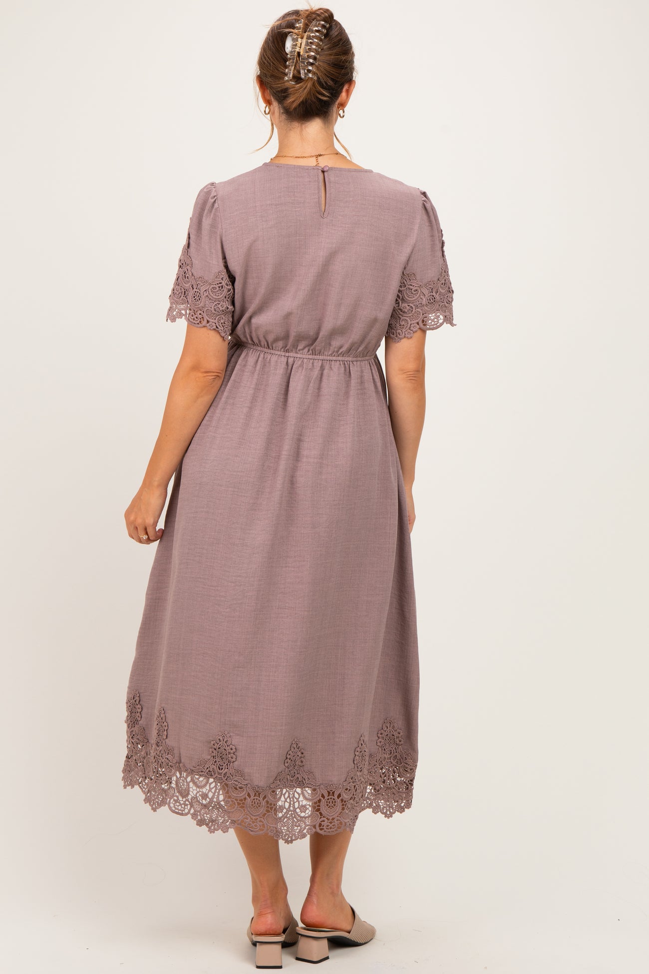 woman wearing a mauve maternity dress with lace details and short sleeves, showing the back view