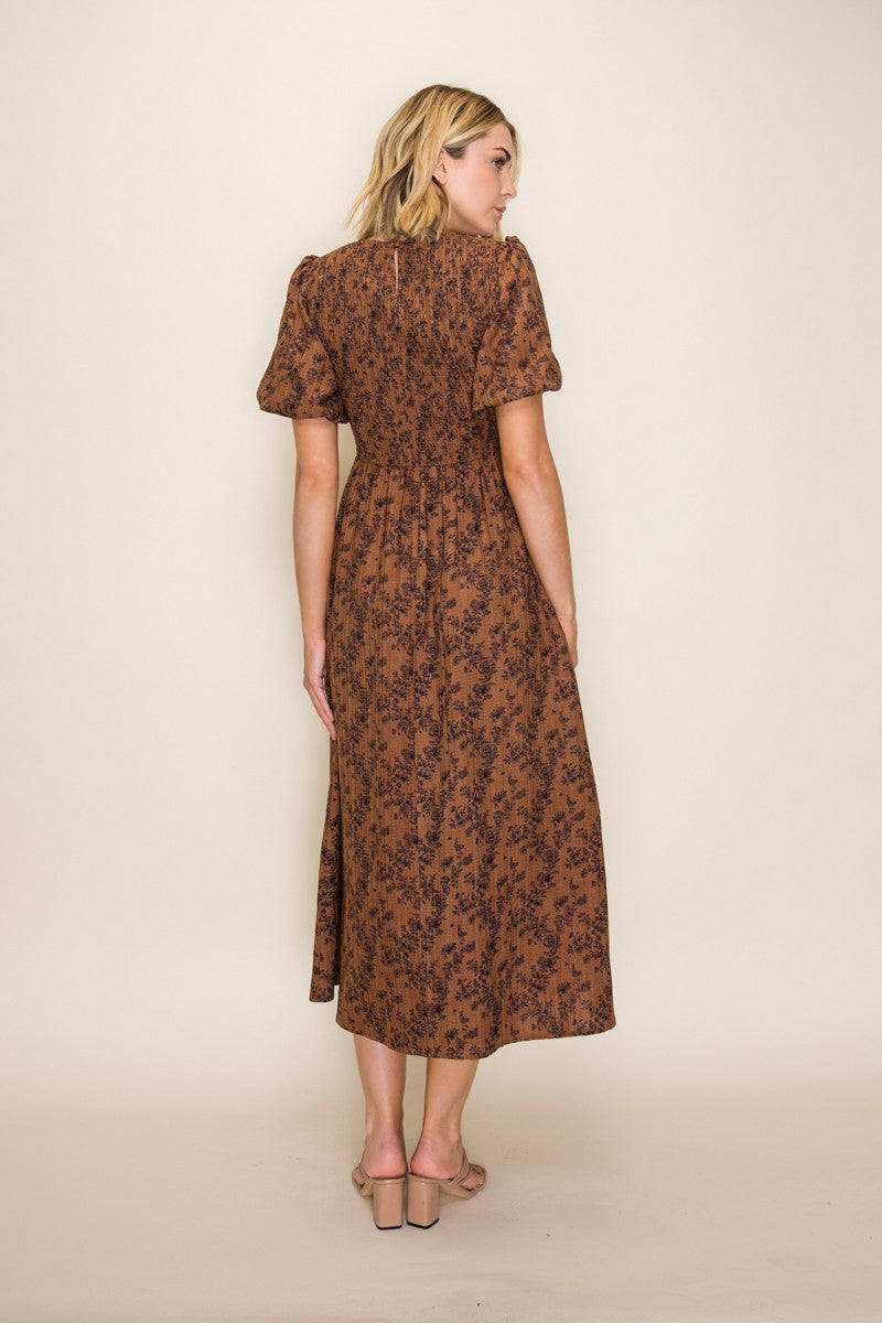 woman wearing a brown floral midi dress with short puff sleeves and a fitted bodice, seen from the back