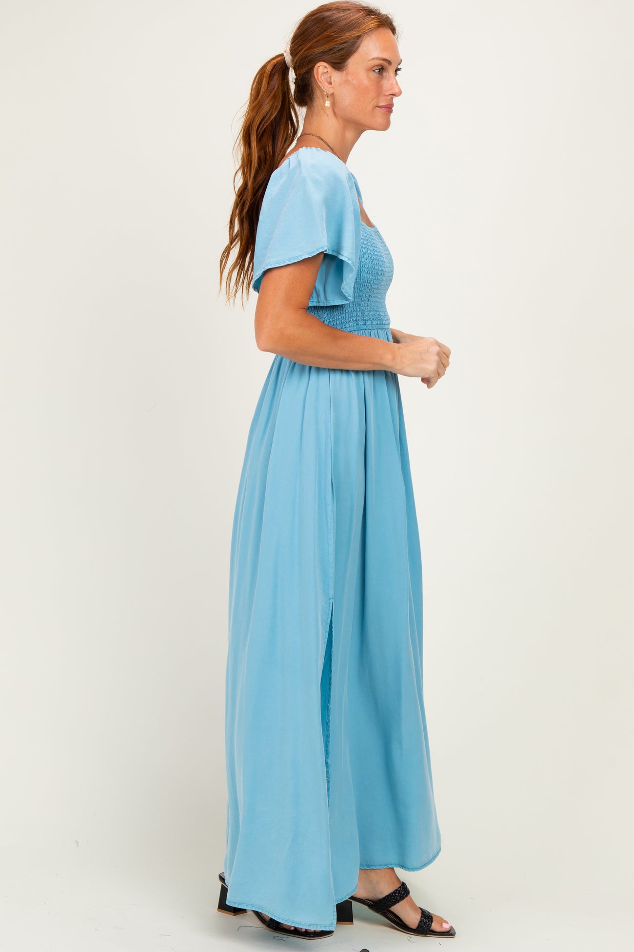 woman wearing a light blue maxi dress with short flutter sleeves and side slits