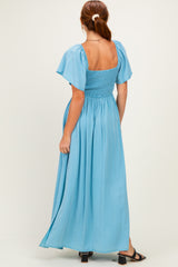 woman wearing a light blue maxi dress with short puff sleeves and a smocked bodice, viewed from the back