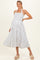 woman wearing a white and navy striped maternity dress with a smocked bodice and a flowing skirt, smiling and posing