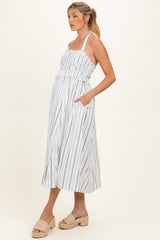 woman wearing a striped maternity dress with a smocked bodice and side pockets, showcasing a baby bump
