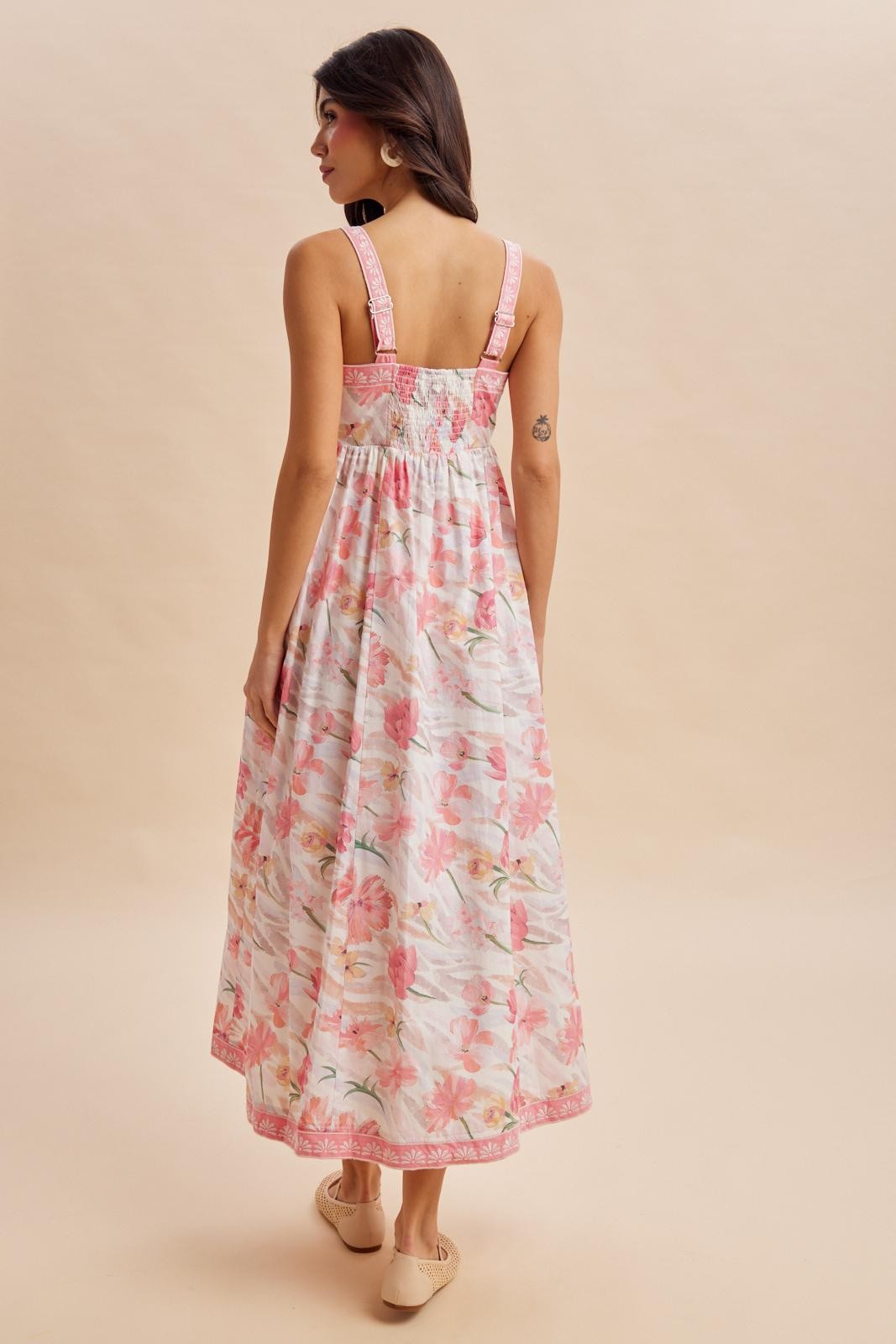 woman wearing a back view of a floral maxi dress with pink and white flowers and adjustable straps