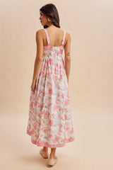 woman wearing a back view of a floral maxi dress with pink and white flowers and adjustable straps