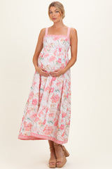 woman wearing a floral maternity maxi dress with adjustable straps and holding her baby bump