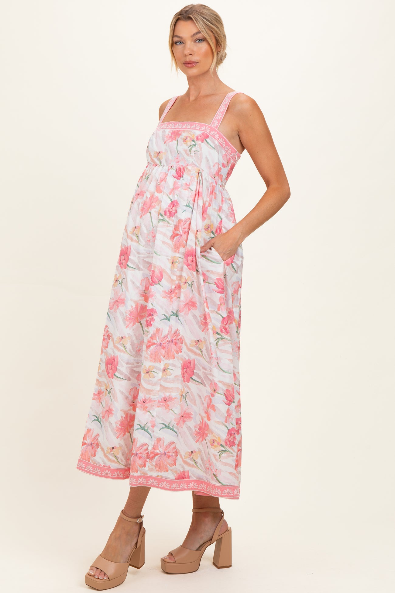 woman wearing a floral maternity maxi dress with a gathered waist and pockets, showcasing her baby bump