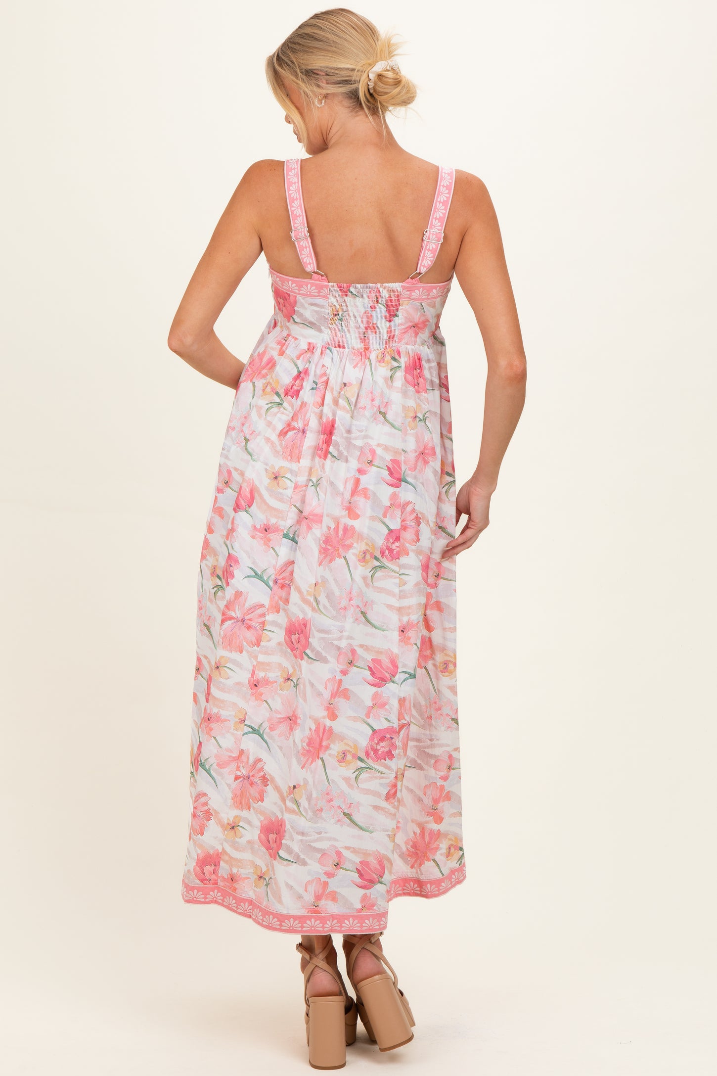 woman wearing a floral maternity maxi dress with pink and pastel colors, showing a baby bump from the back