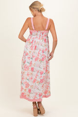 woman wearing a floral maternity maxi dress with pink and pastel colors, showing a baby bump from the back