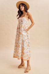 woman wearing a floral maxi dress with a gathered bodice and pockets, paired with a straw hat and sandals