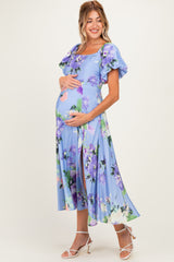 woman wearing a light blue floral maternity dress with short puff sleeves and a visible baby bump