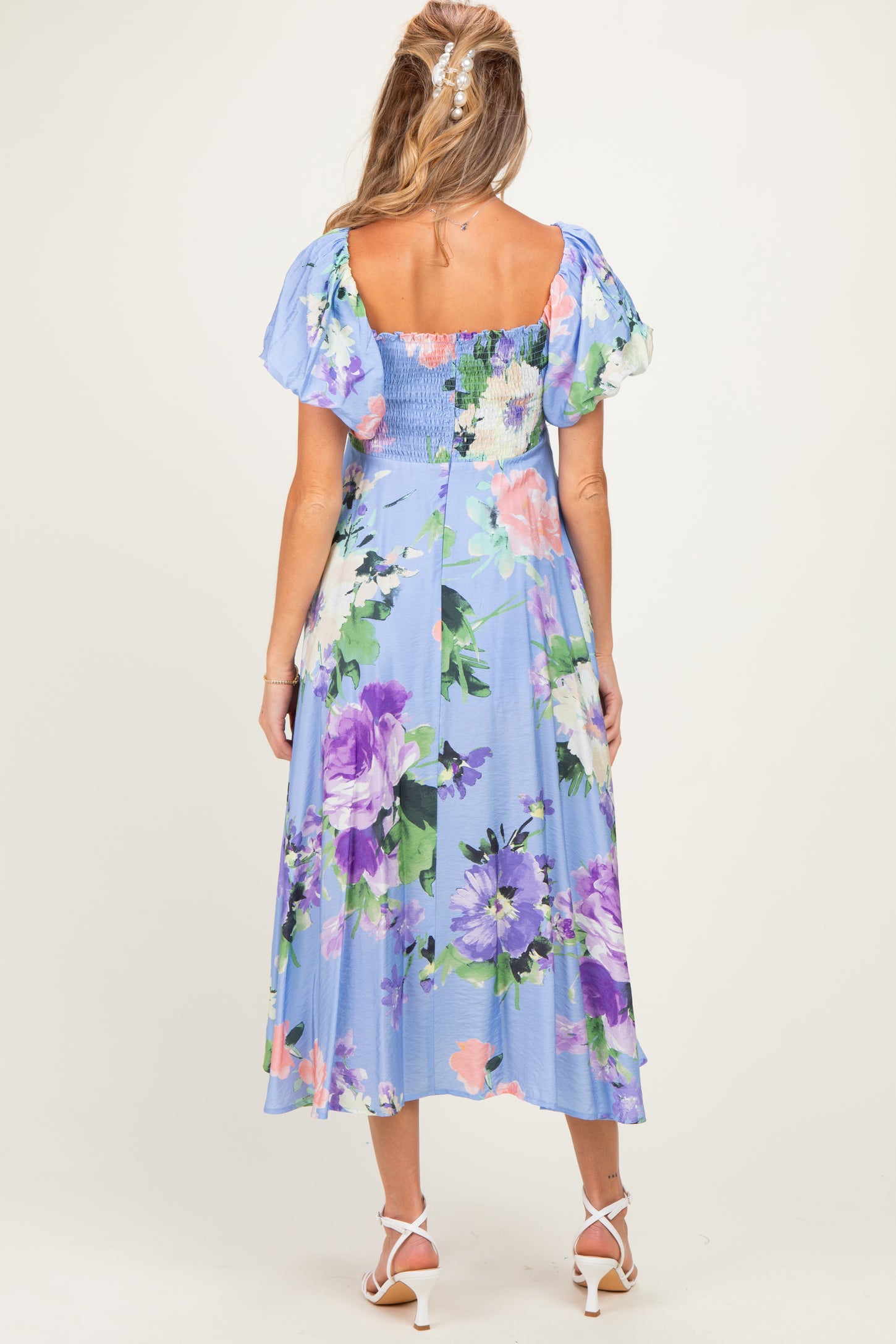 woman wearing a floral maternity dress with a smocked bodice and puff sleeves, showing a baby bump from the back