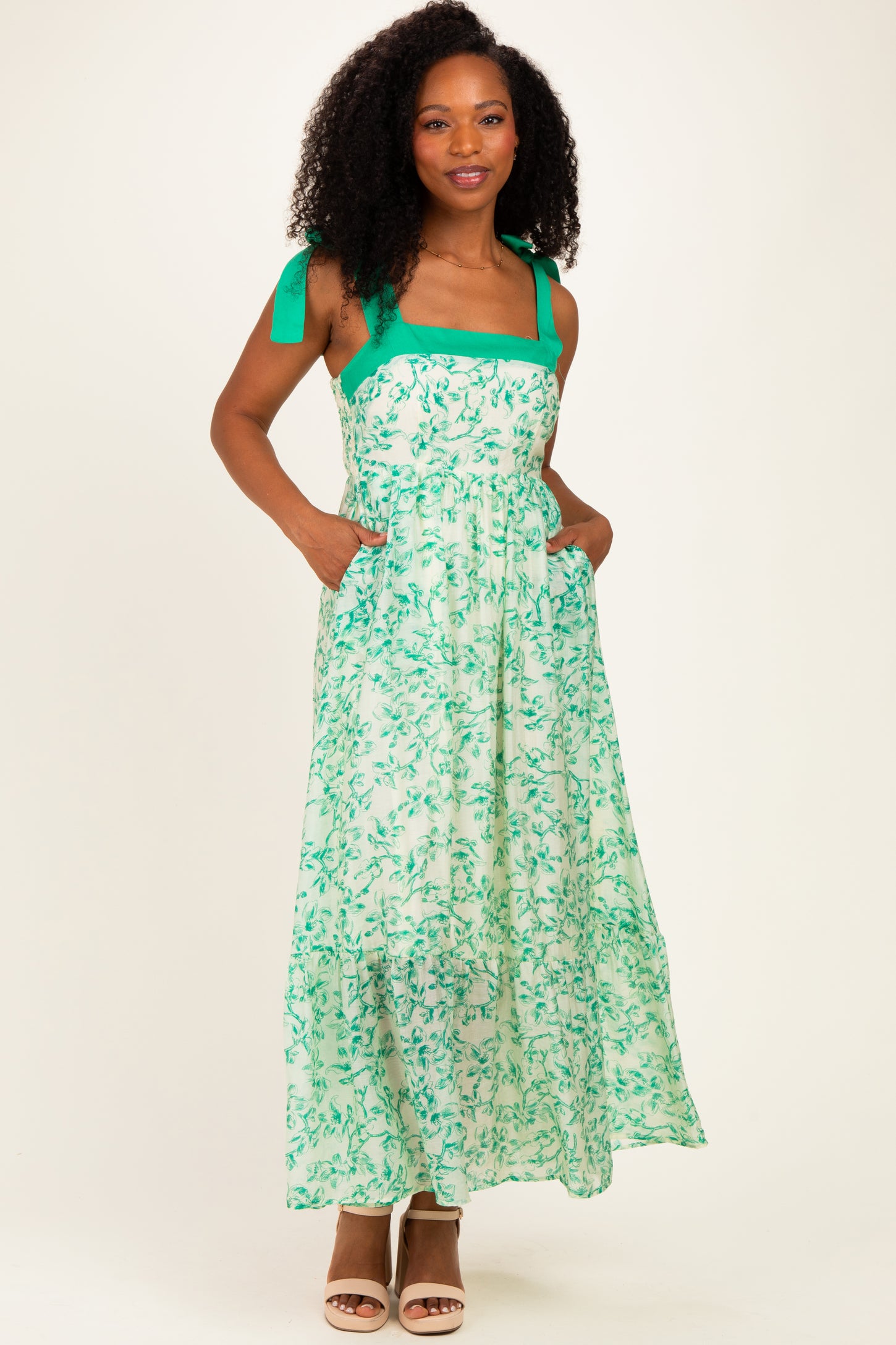 woman wearing a green and white floral maxi dress with tie straps and pockets