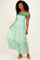 woman wearing a green and white floral maxi dress with tie-shoulder straps and a tiered bottom