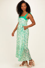 woman wearing a green and white floral maxi dress with adjustable straps and pockets