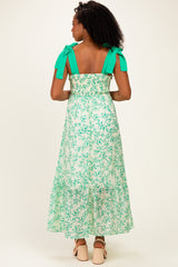 woman wearing a green floral maxi dress with smocked back and bow shoulder straps, shown from the back
