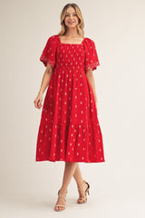 woman wearing a red midi dress with puff sleeves and a tiered skirt displaying gold dot patterns