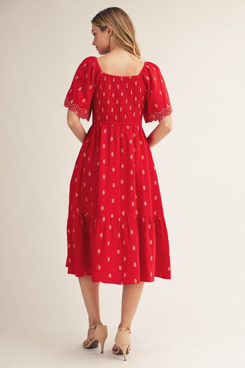 woman wearing a red midi dress with puff sleeves and golden embroidery, showing a back view