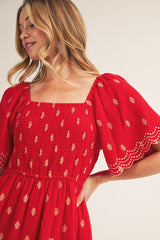 woman wearing a red smocked dress with puff sleeves and gold embellishments