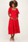 woman wearing a red patterned maternity dress with puff sleeves and holding her baby bump