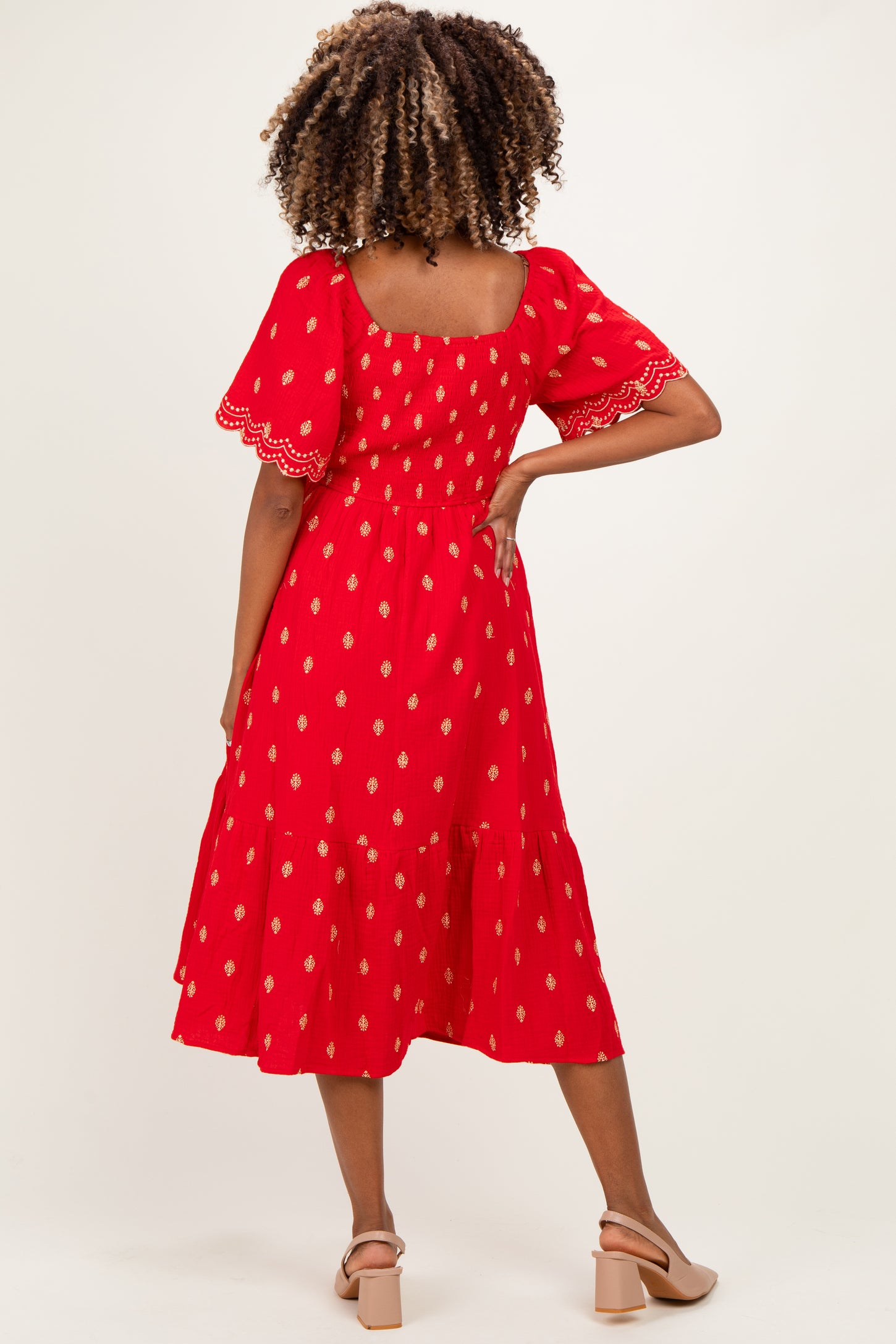 woman wearing a red maternity dress with puff sleeves and a tiered skirt, showing the back view