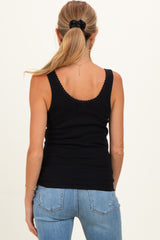 woman wearing a black ribbed maternity tank top viewed from the back with light blue jeans