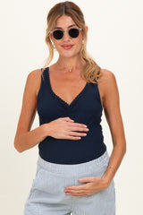 woman wearing a navy blue maternity tank top with lace trim and holding her baby bump