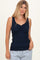 woman wearing a navy blue sleeveless top with a smocked front and scalloped neckline