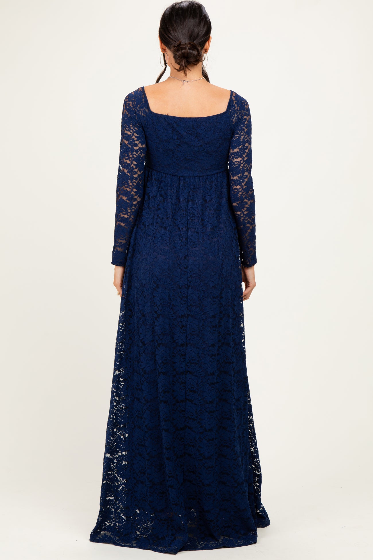 woman wearing a navy blue long sleeve lace maxi dress, showing the back view and full-length style