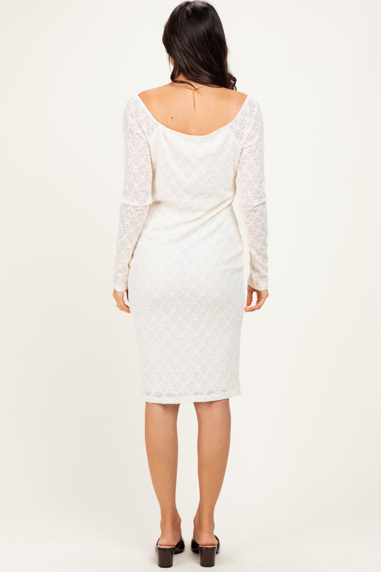 woman wearing a white lace long sleeve midi dress, showcased from the back with a fitted silhouette