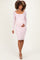 woman wearing a light pink lace long sleeve maternity dress and showing her baby bump