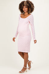 woman wearing a light pink long sleeve lace maternity dress, showing a visible baby bump and standing confidently