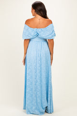 woman wearing a light blue off-the-shoulder lace maternity maxi dress, showing a flowing silhouette from the back