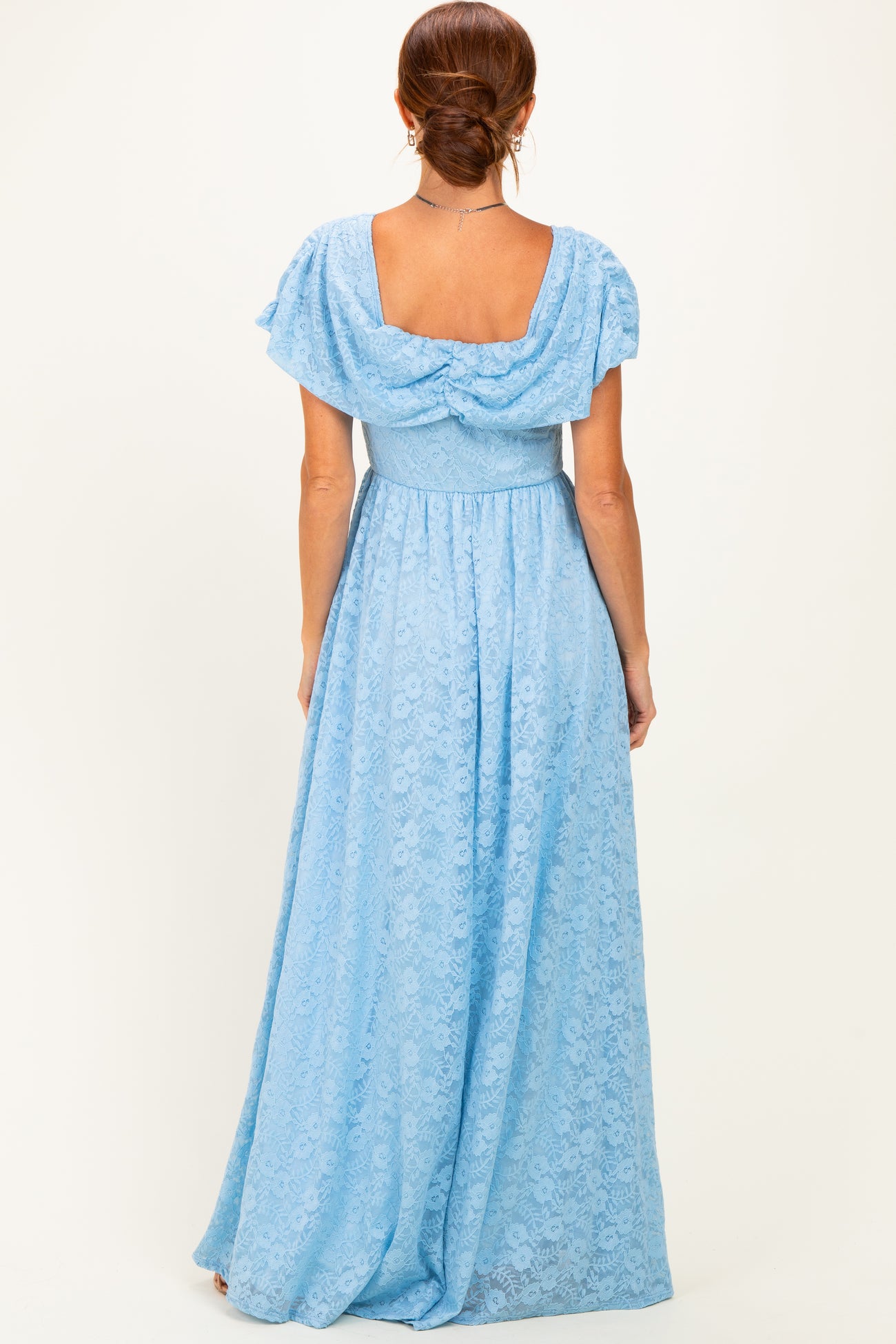 woman wearing a light blue lace maxi dress with flutter sleeves and a cinched waist, showcasing the back view