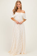 woman wearing a cream off-the-shoulder lace maxi dress with a tie detail at the bust