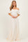 woman wearing a cream off-the-shoulder lace maxi dress with a tie detail at the bust