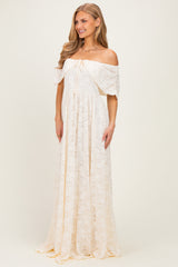 woman wearing a cream off-the-shoulder lace maxi dress with a drawstring waist and flowing skirt