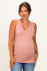 woman wearing a dusty pink v-neck maternity tank top accentuating her baby bump and paired with blue jeans