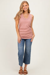 woman wearing a dusty rose sleeveless v-neck top and blue wide-leg jeans, smiling while posing on a light background