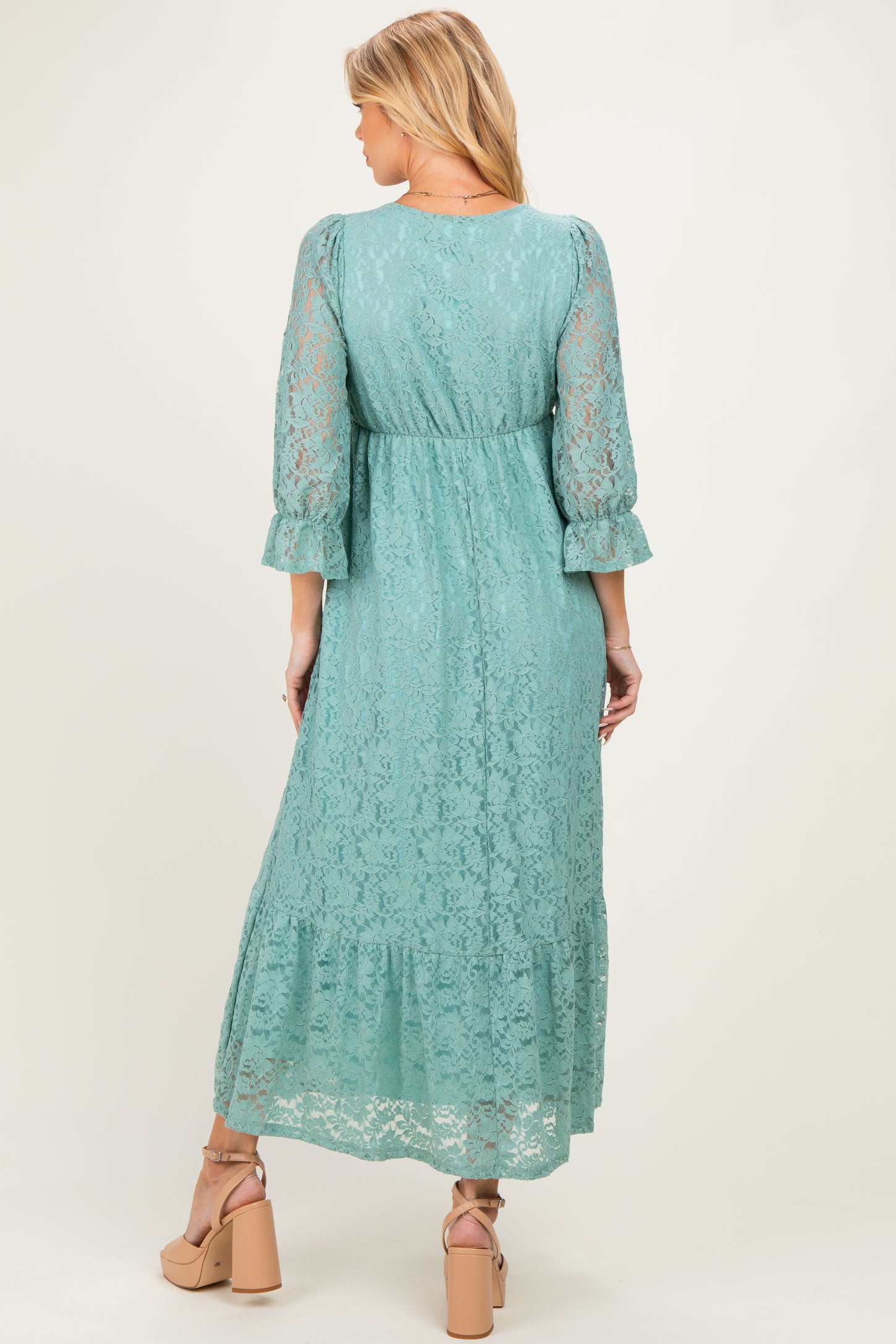woman wearing a mint green lace maternity maxi dress with three-quarter sleeves and a ruffled hemline