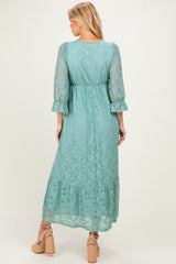 woman wearing a mint green lace maternity maxi dress with three-quarter sleeves and a ruffled hemline
