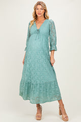woman wearing a green lace maternity dress with 3/4 sleeves and a gathered waist, showing her baby bump