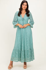 woman wearing a light teal lace maxi dress with a tie front and bell sleeves